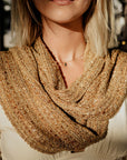 Model wearing the handwoven scarf with blurred trees and a street in the background