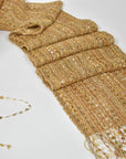 Golden textured scarf laying on a table with a cone of one of the textured yarns