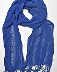 Indigo blue handwoven scarf styled on a white table. Check out the puckers.