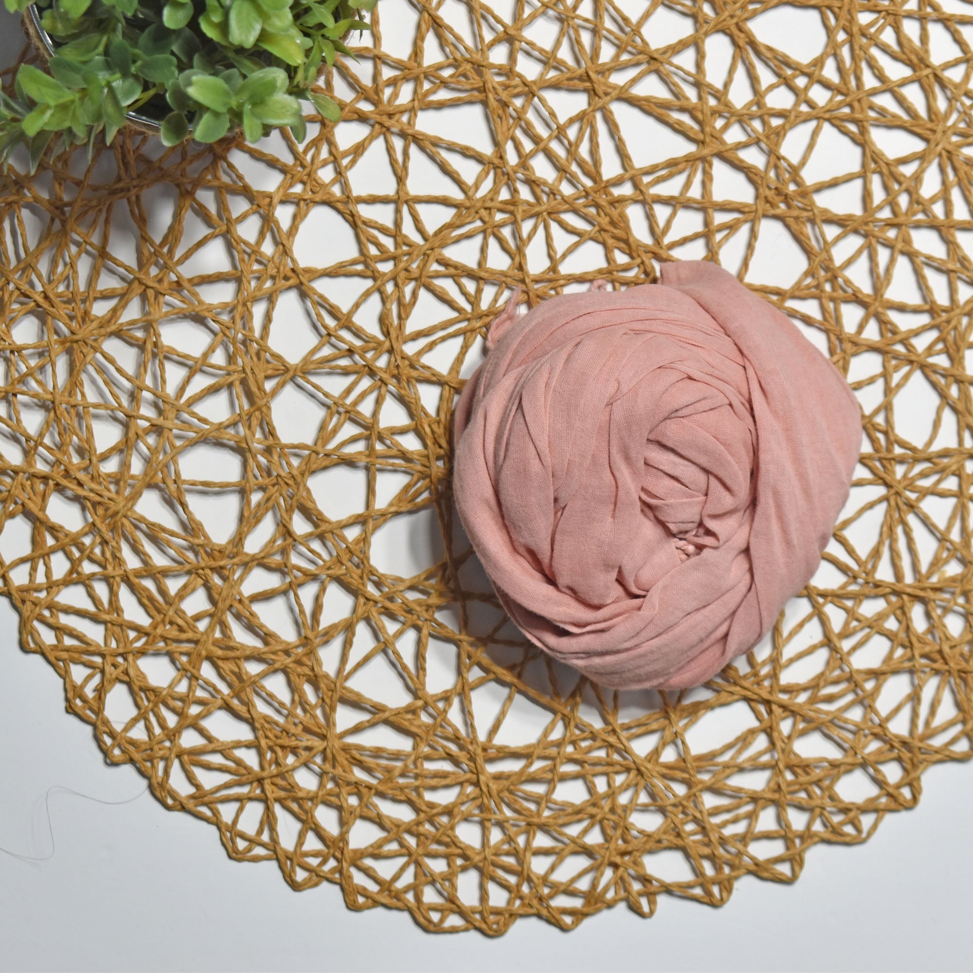 Rose hand-painted scarf on a white table with a plant and rattan doily