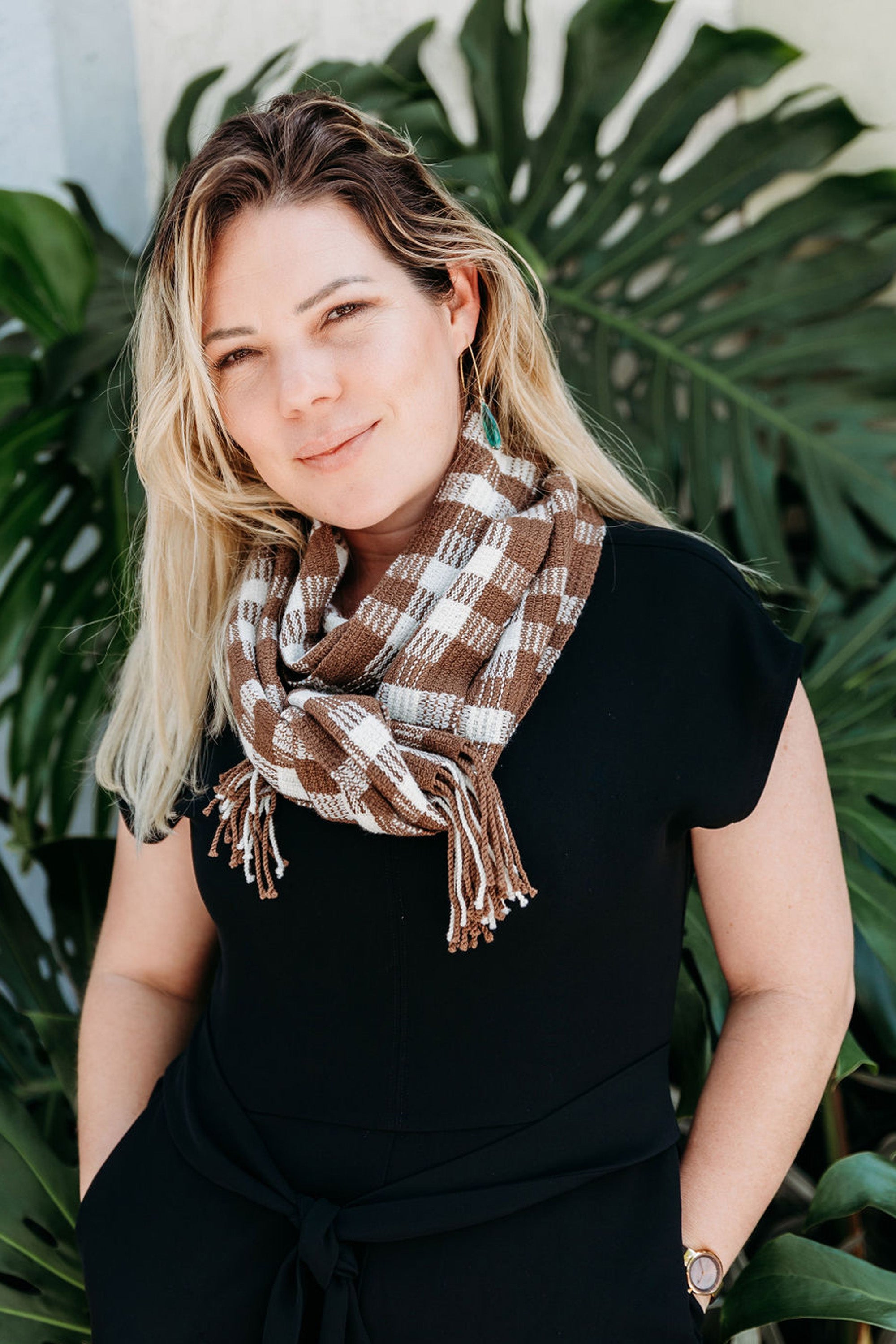 Chestnut brown + white handwoven wool scarf wrapped on a model. The model is standing in from of a tree.