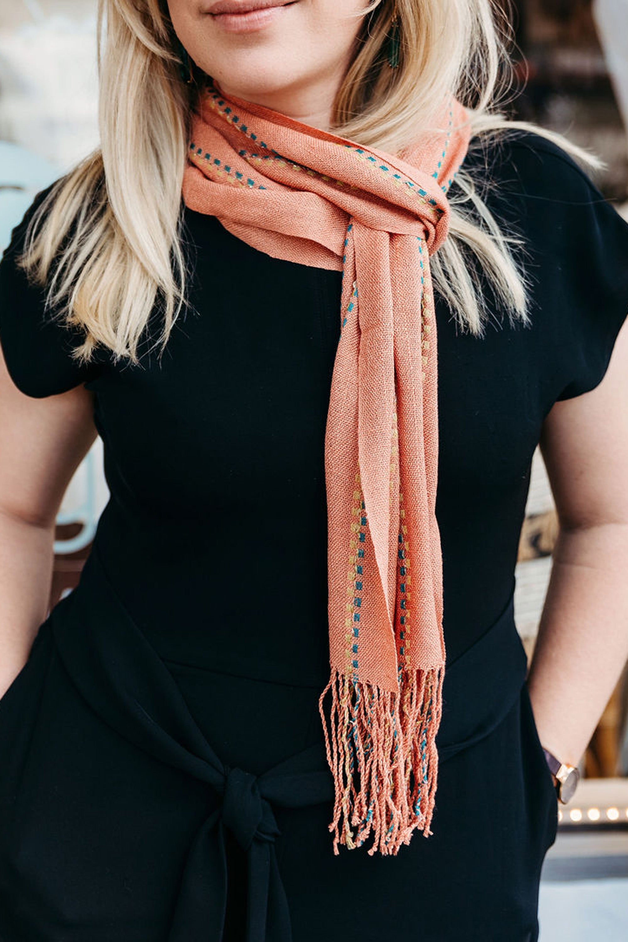 Model is styling a handwoven peach with sparkles scarf