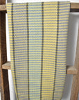 Green, yellow, turquoise, and black colored towel hanging on a wooden ladder