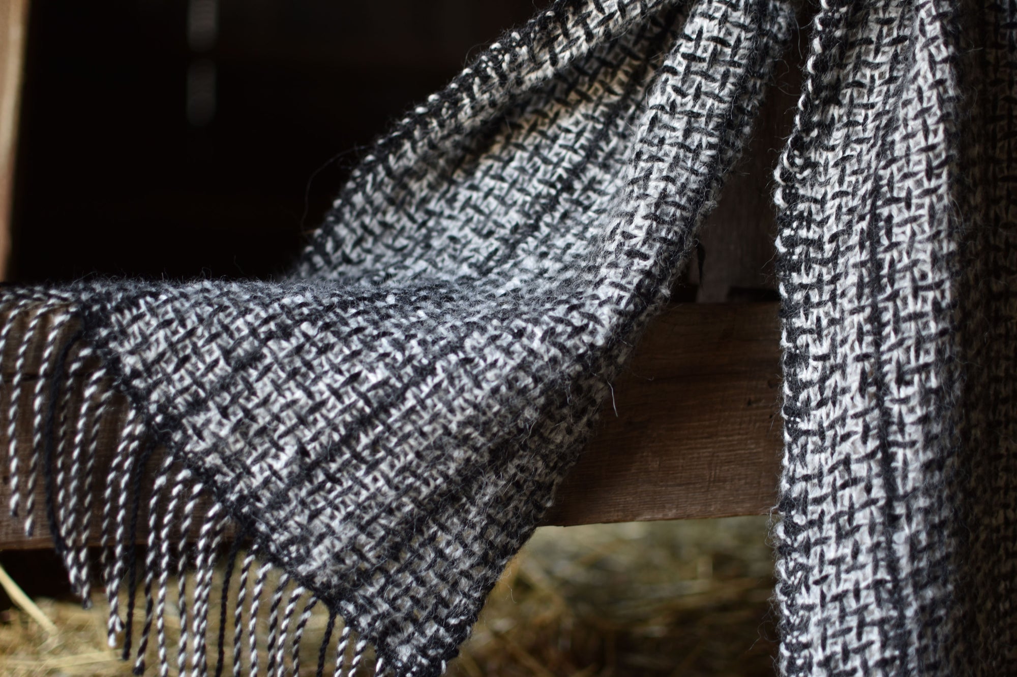 Close-up of the hand twisted fringes on the handwoven scarf. The background is the interior of our barn.