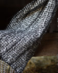 Close-up of the hand twisted fringes on the handwoven scarf. The background is the interior of our barn.