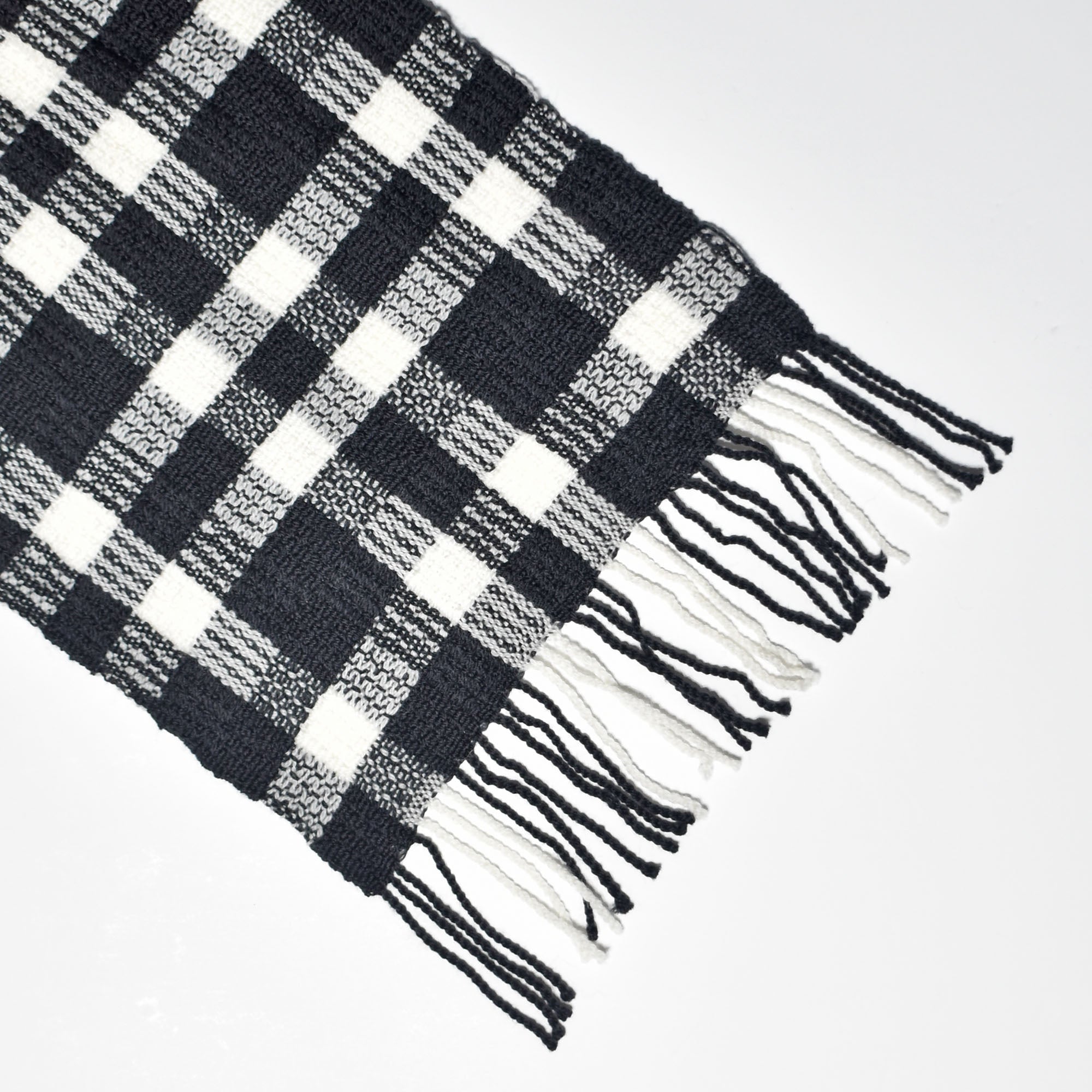 Close-up of the hand twisted fringe on the black + white handwoven wool scarf