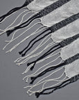 Close-up of the hand twisted fringe on the black and white striped handwoven scarf