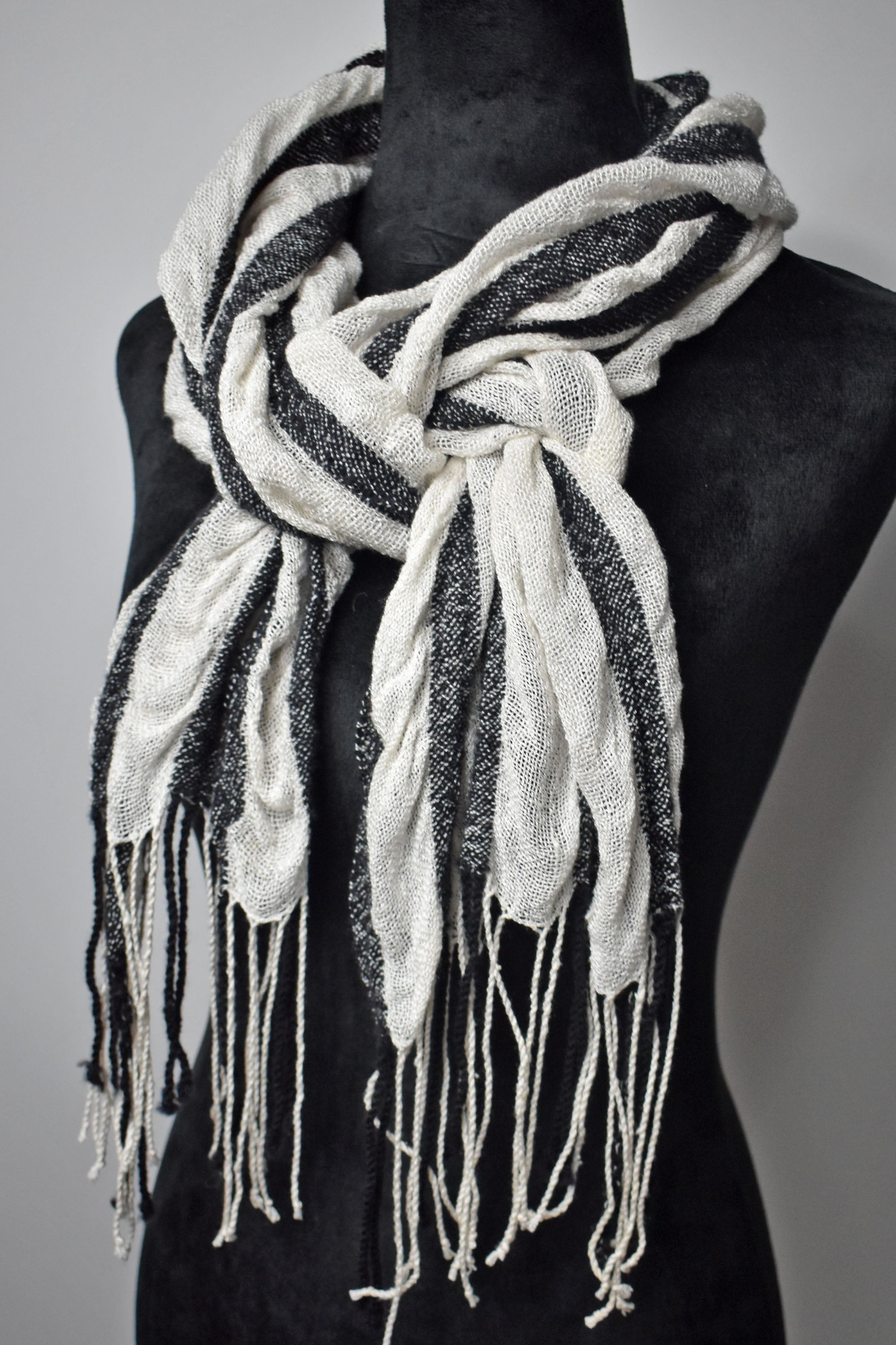 Black merino wool with white up-cycled yarns striped puckered scarf on a mannequin.