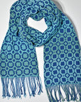 Blue + green handmade scarf styled on a white table. Check out the different designs on the front and back