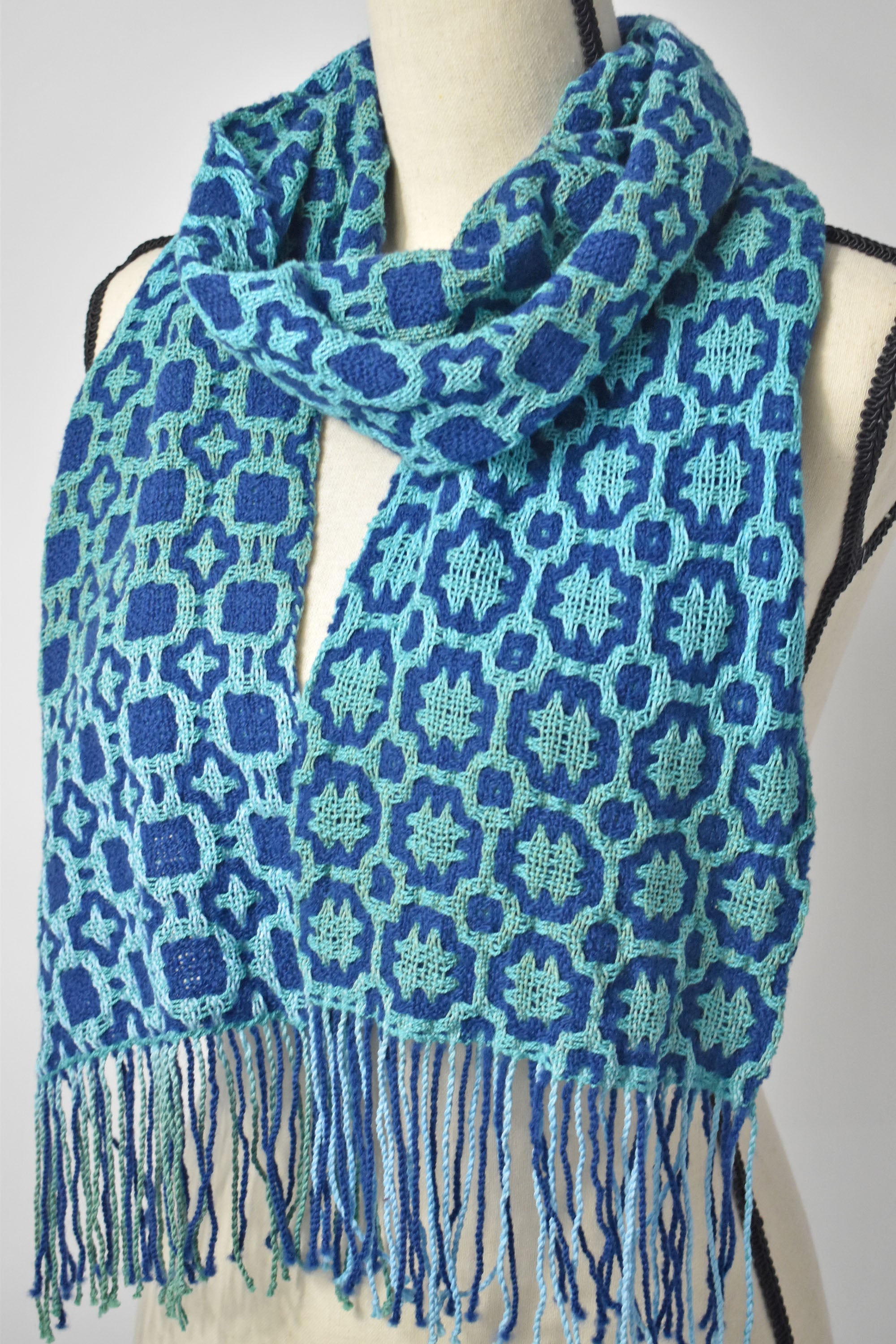 Blue + green hand painted and handwoven textured scarf on a mannequin.