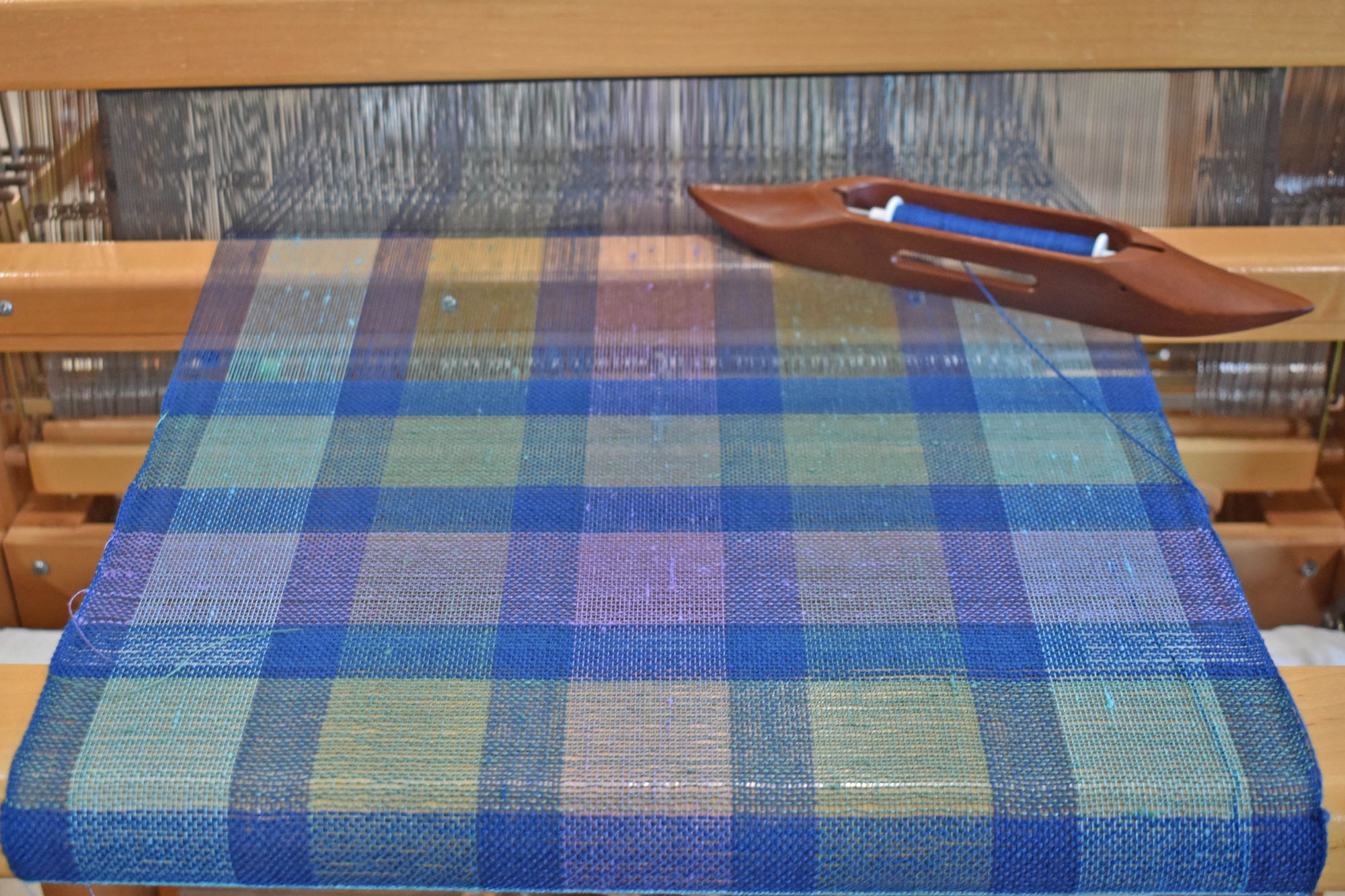 The blues and purple handwoven scarf on the loom.