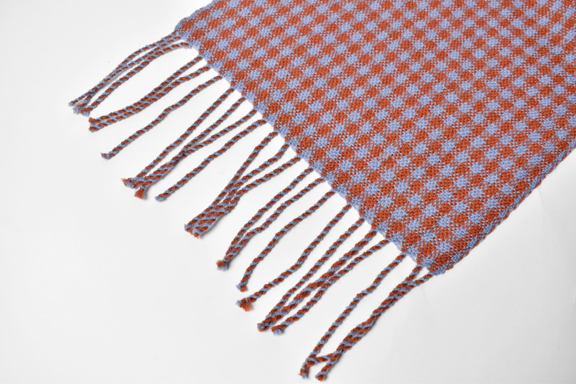 Close-up of the hand twisted fringe on blue + orange handwoven merino wool scarf