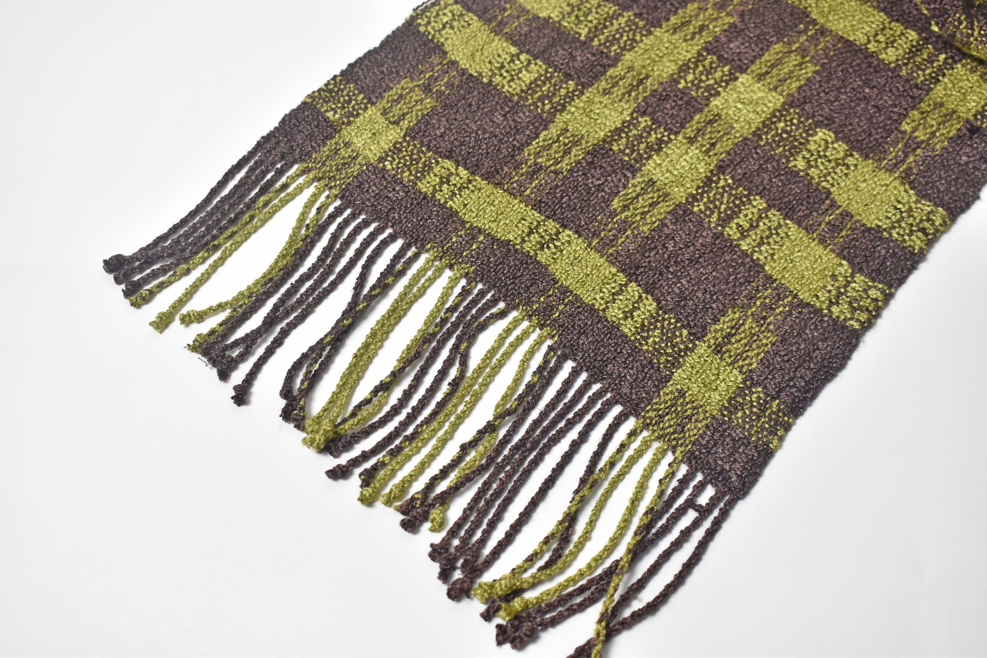 Close-up the hand twisted fringe on the brown + green handwoven scarf