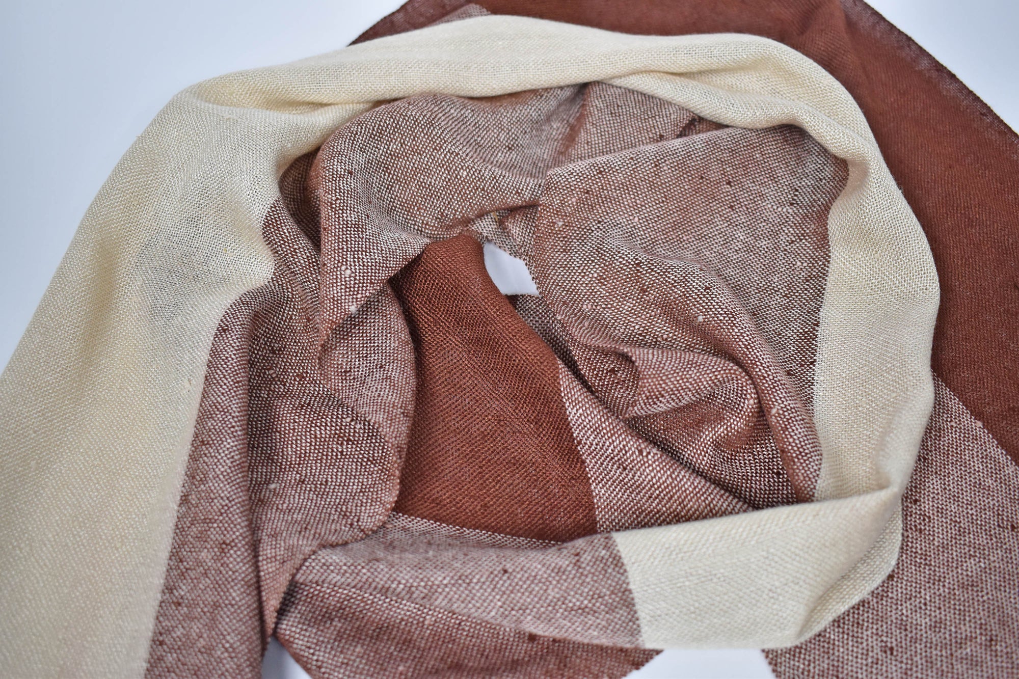 Scarf draped on a table to show the different colors of the brown and cream