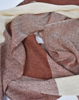 Scarf draped on a table to show the different colors of the brown and cream