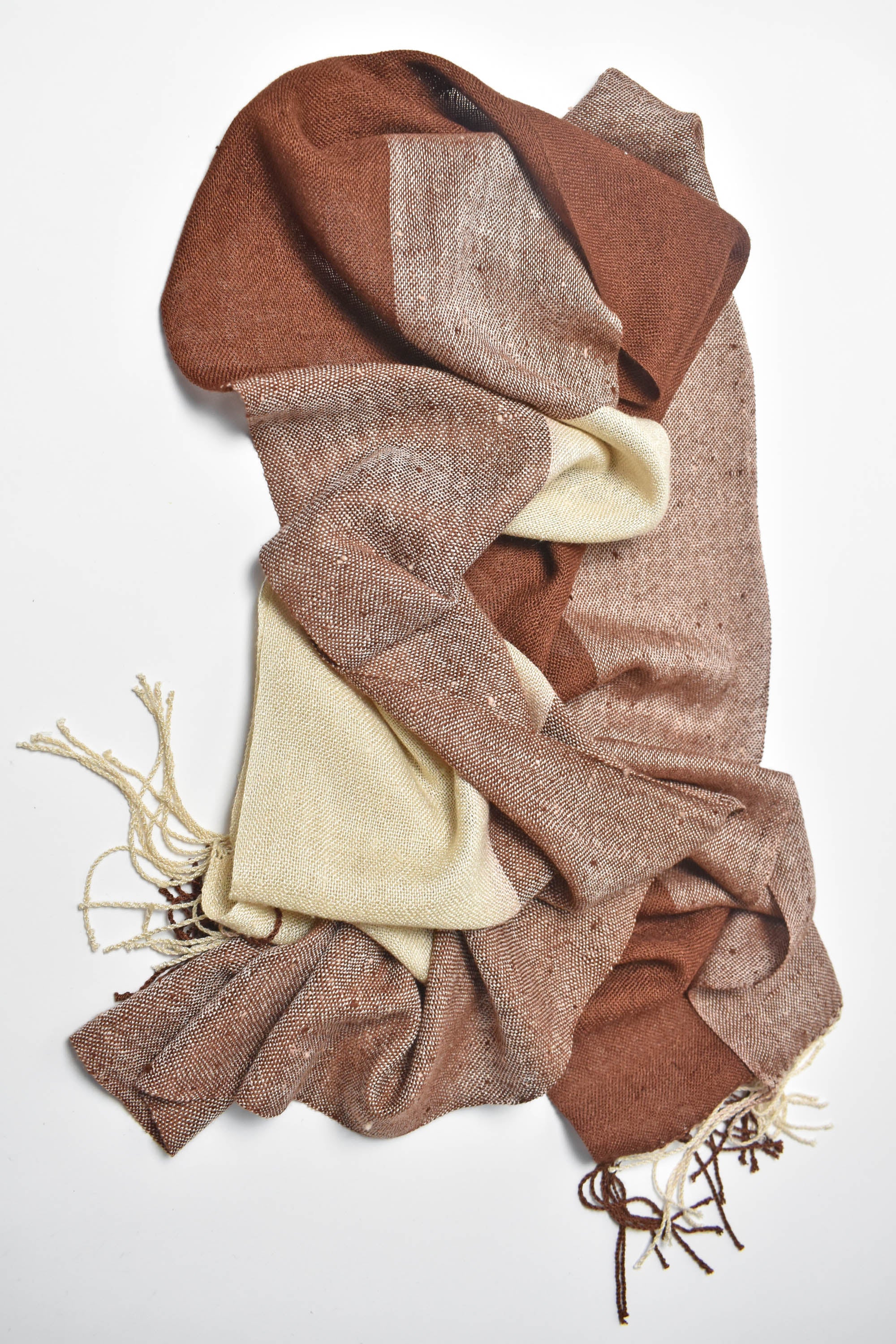 Brown + cream handwoven scarf draped on a white table