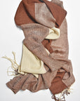 Brown + cream handwoven scarf draped on a white table