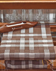 Chestnut brown + white scarf being handwoven on a wooden floor loom