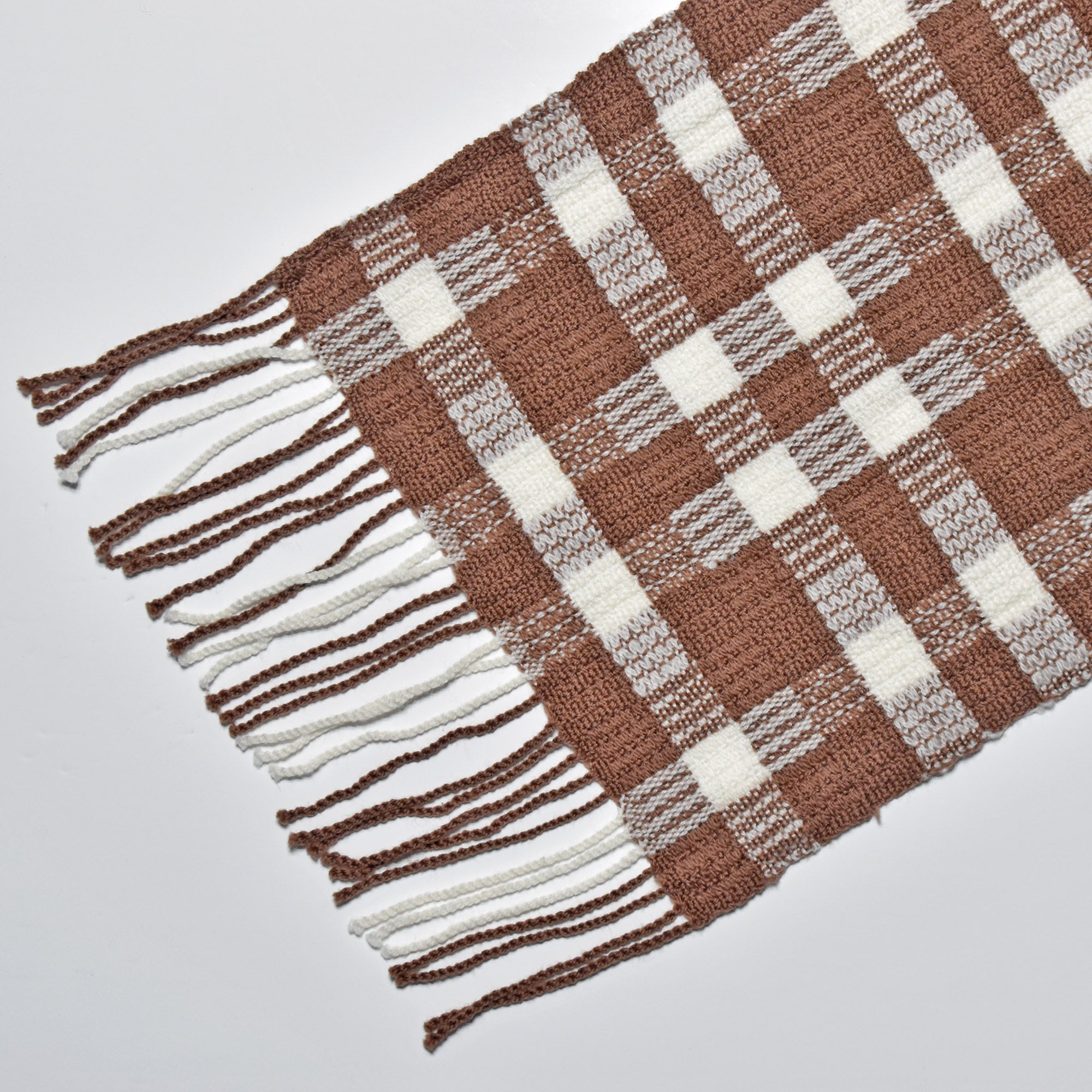 Close-up pf the hand twisted fringe on the chestnut brown + white handwoven wool scarf