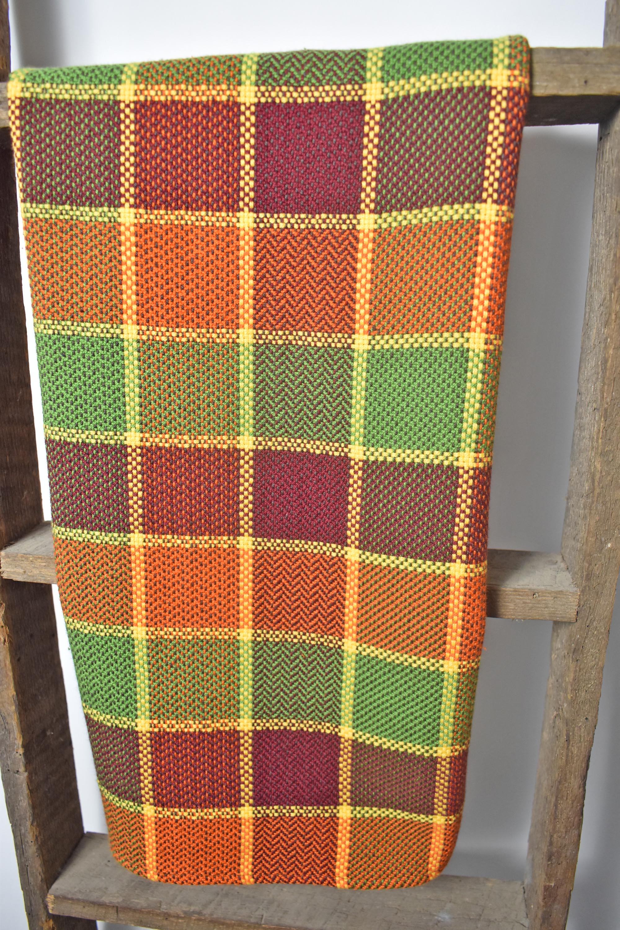 Fall inspired handwoven organic cotton towel hanging on a wooden ladder