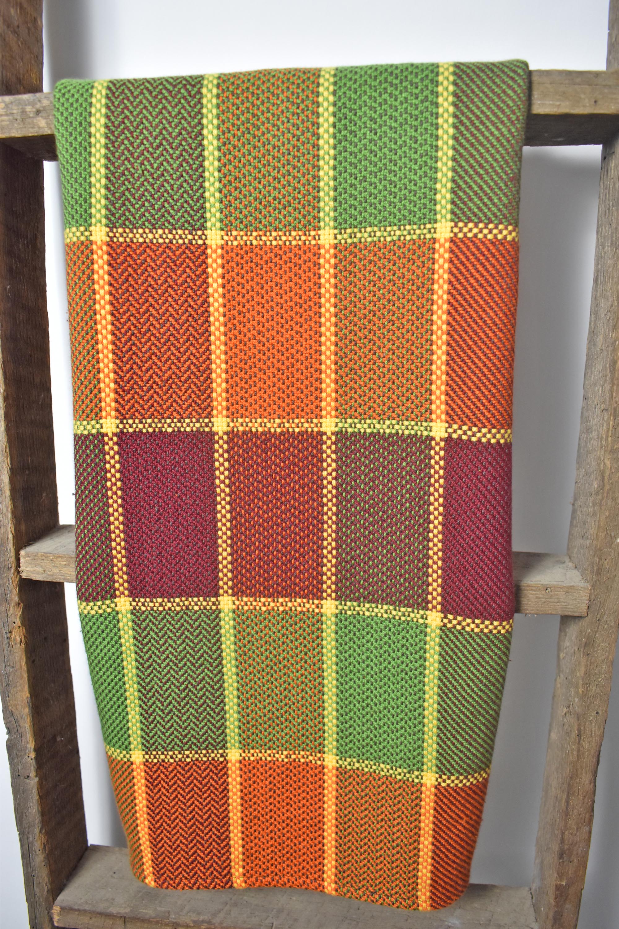 Plaid handwoven towel in a plaid design hanging on a ladder