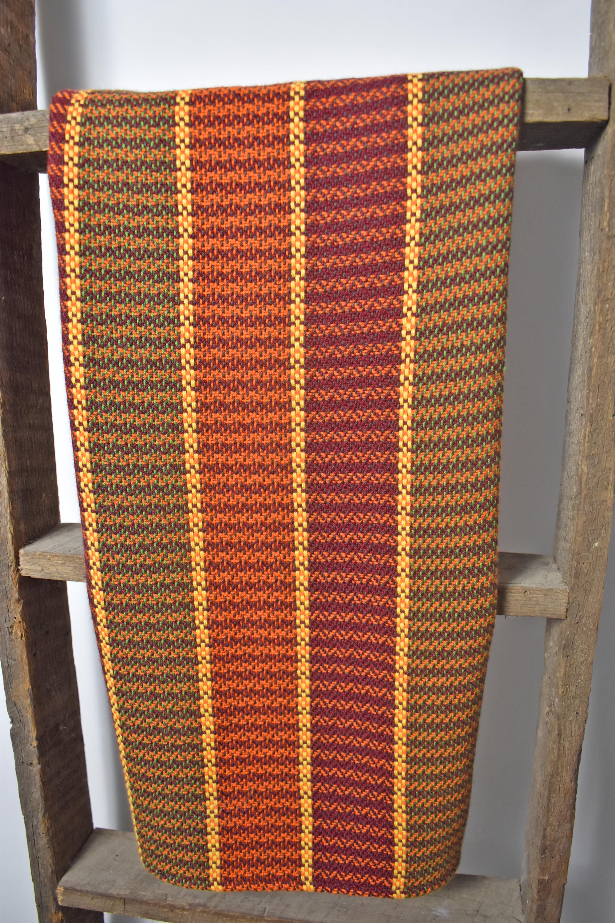 On a wooden ladder, is a handwoven cotton towel