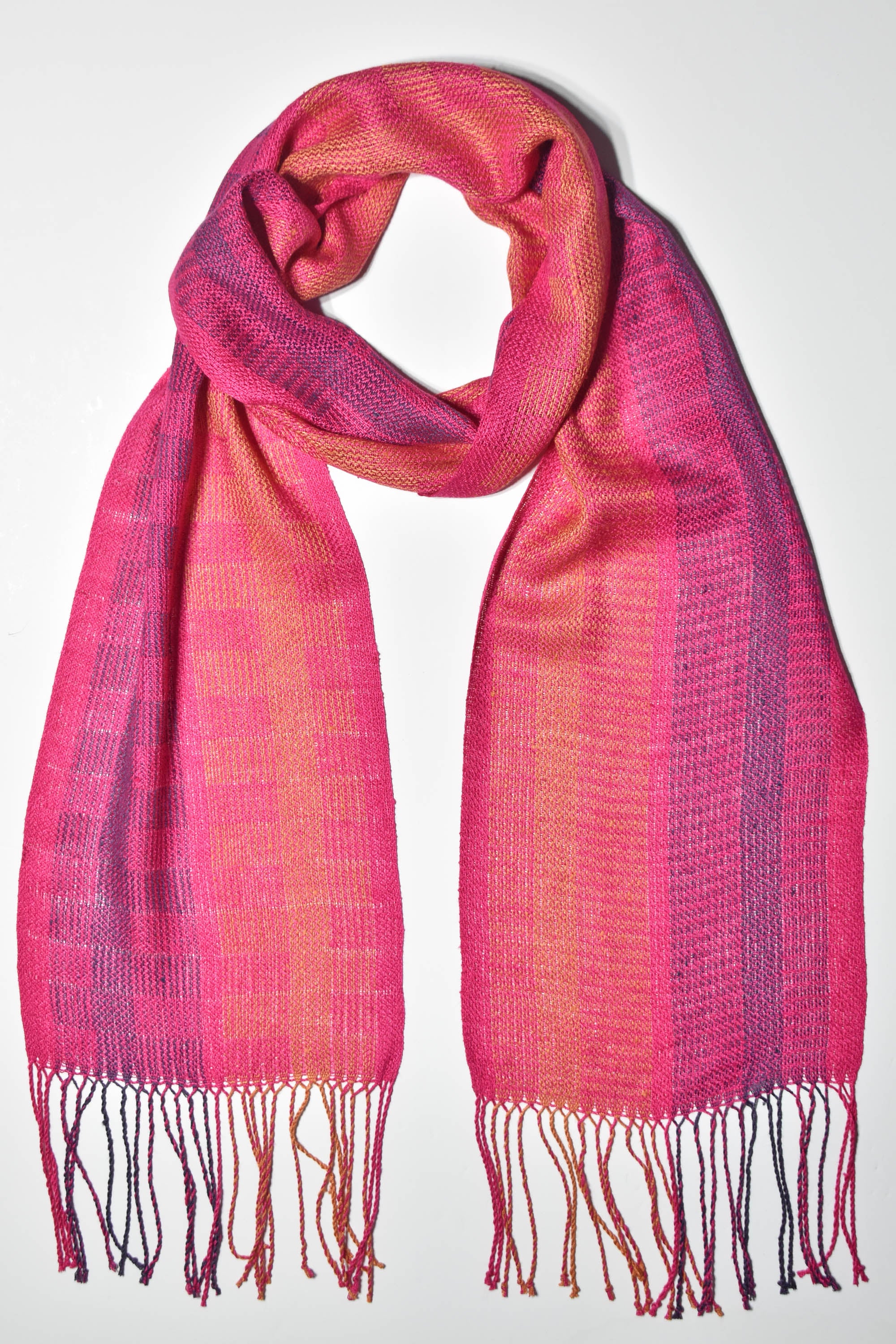 Fuchsia handwoven scarf draped on a white table. Check out the block pattern.