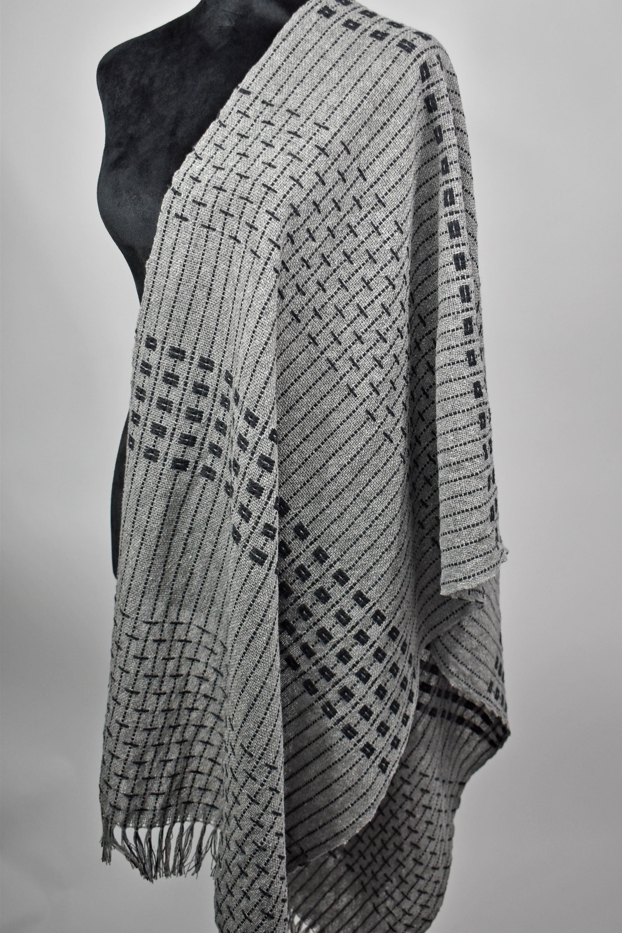 A full view of the gray handwoven scarf draped over a mannequin.