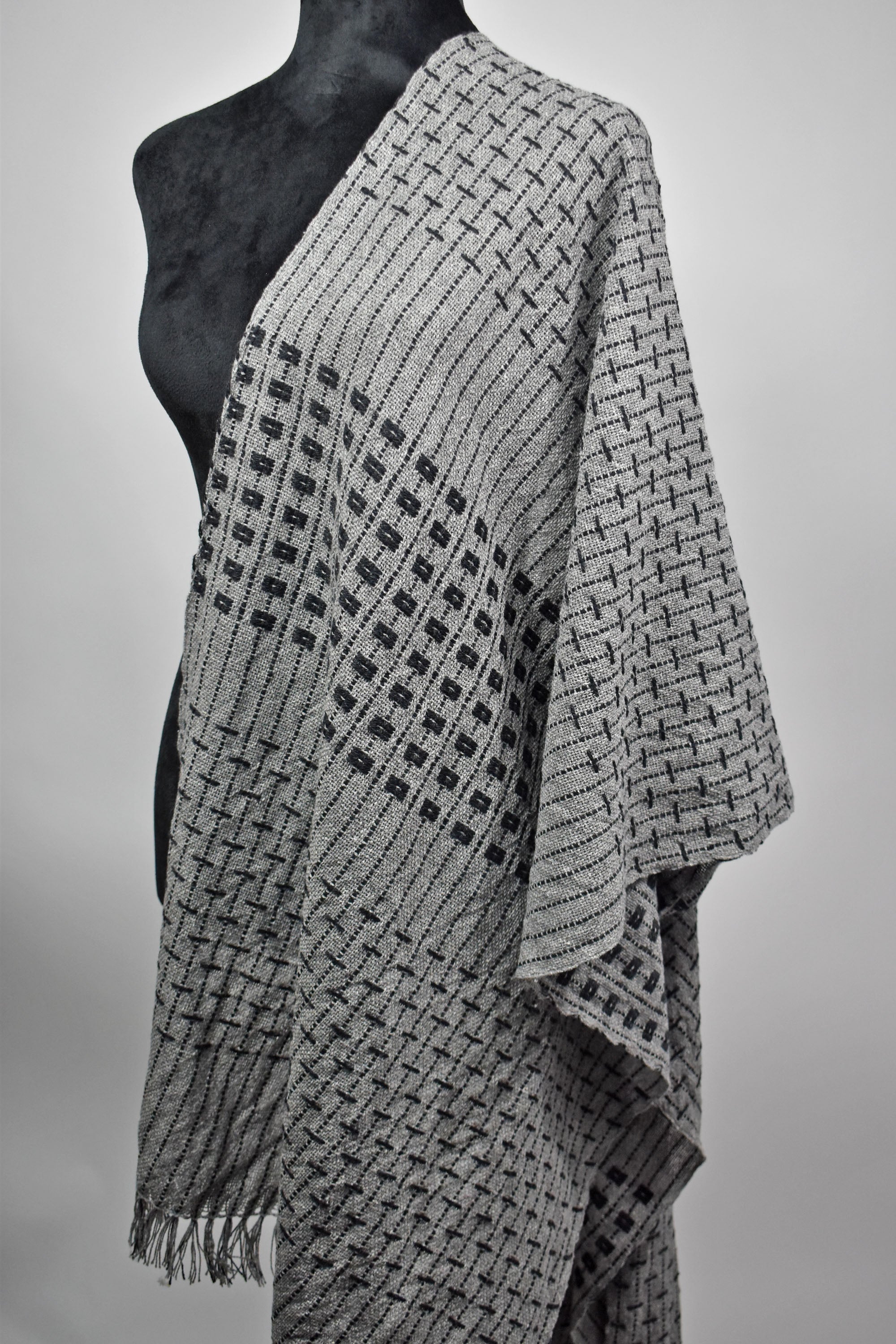 Another view of the handwoven women's gray shawl draped over a mannequin.