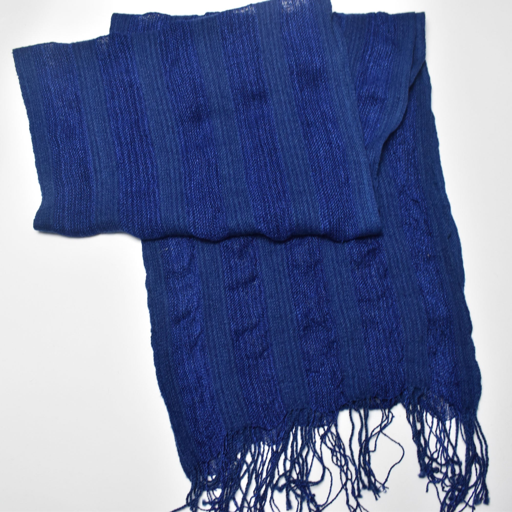 Bird&#39;s eye view of the indigo blue handwoven scarf styled on a white table