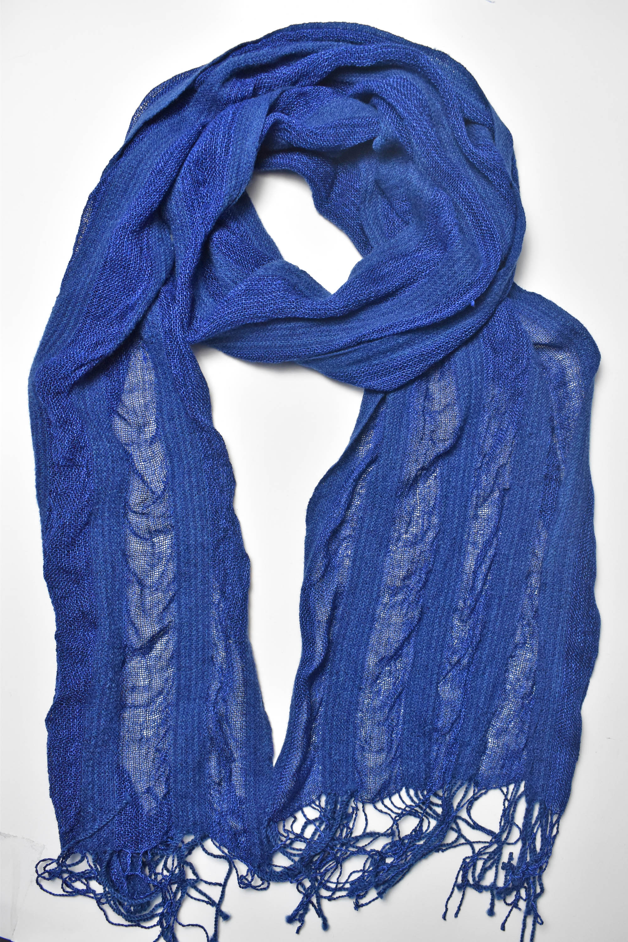 Indigo blue handwoven scarf styled on a white table. Check out the puckers.