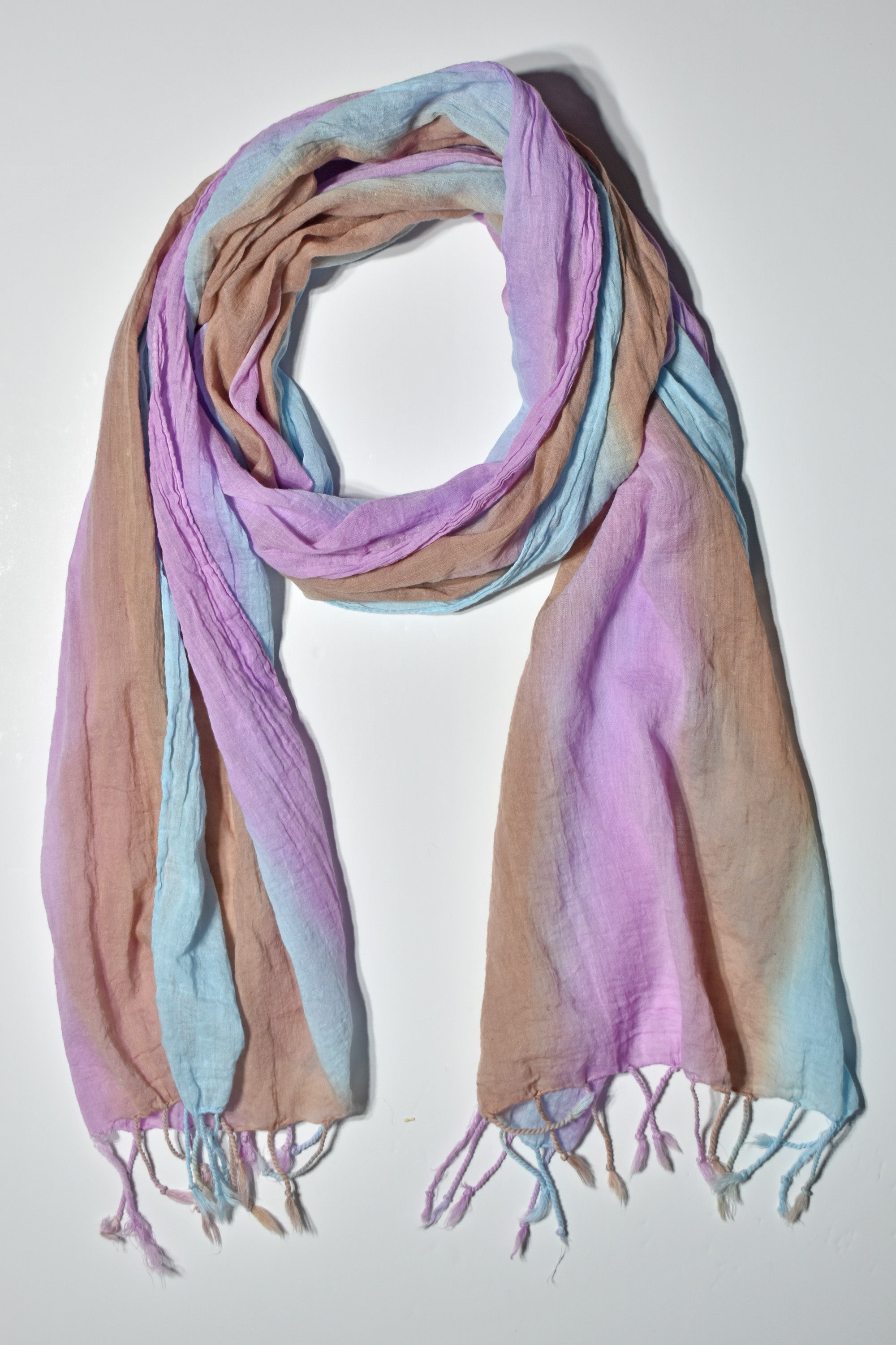 Blue, pink, and brown hand-painted cotton scarf wrapped on a white table