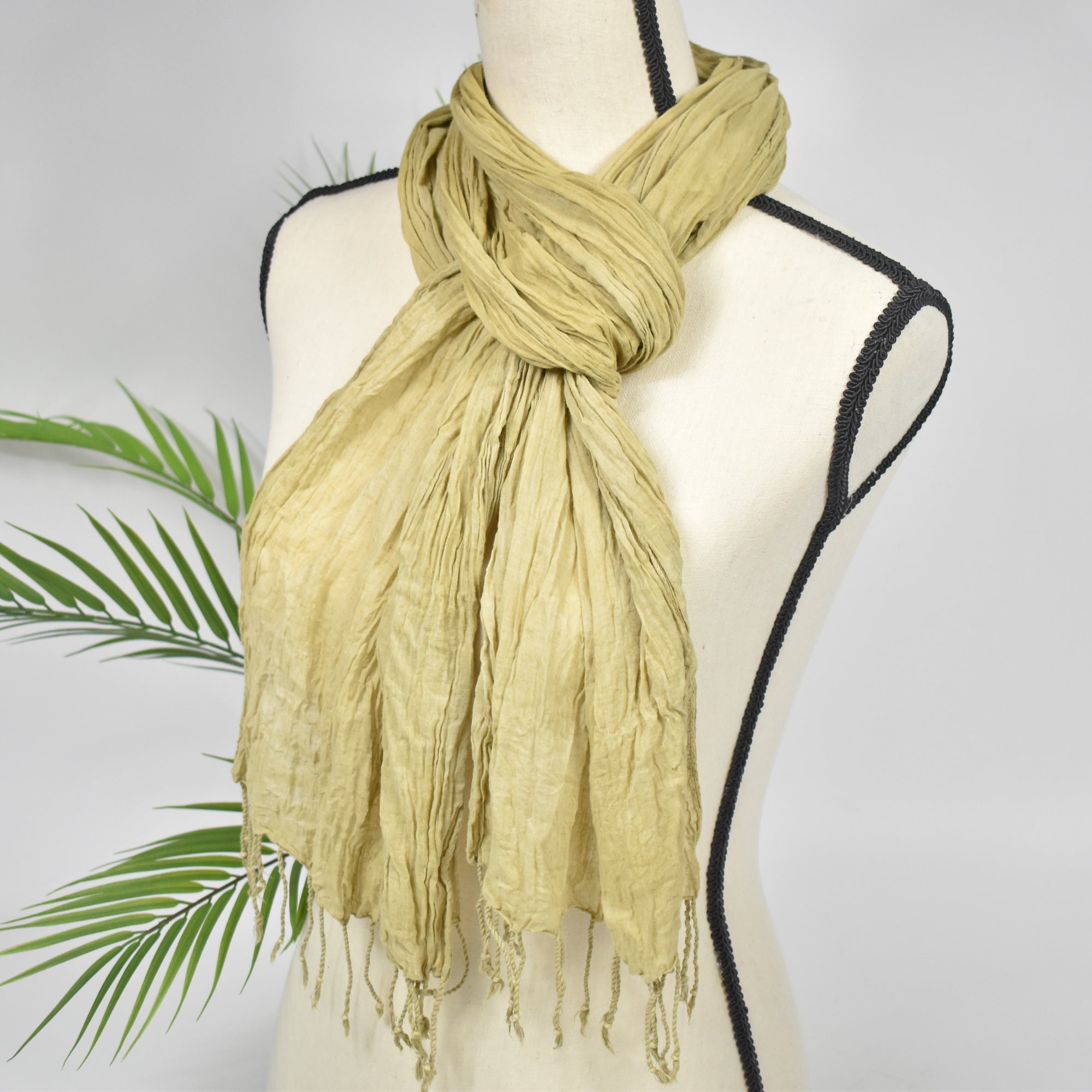 Green tea color hand-painted scarf on a mannequin with a plant in the background.