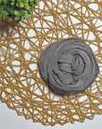 Charcoal gray hand-painted scarf on a white table with a plant and rattan doily