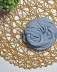 Sky color hand-painted scarf on a white table with a plant and rattan doily