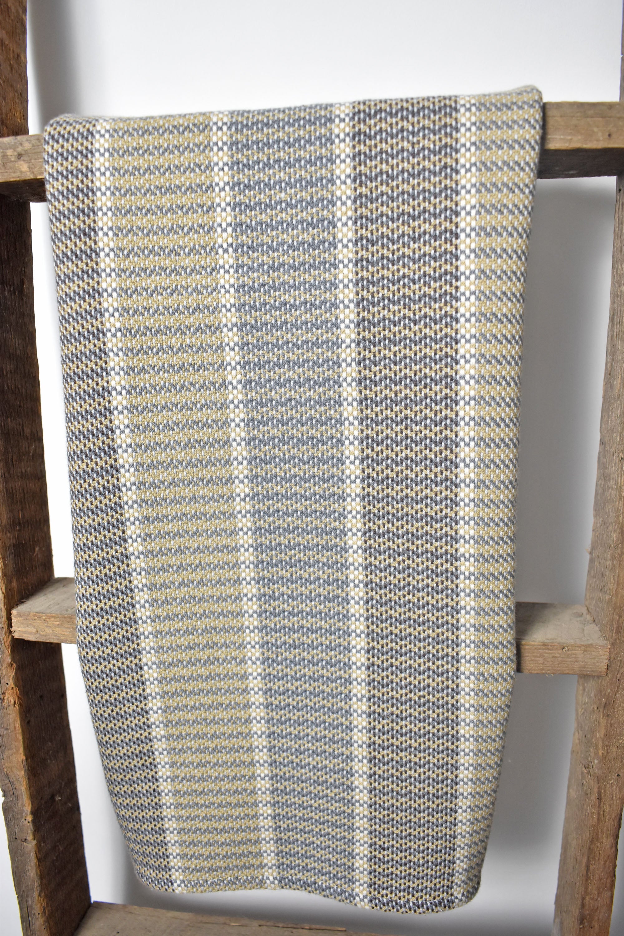 Hanging on a wooden ladder is a neutral handwoven organic cotton dish towel