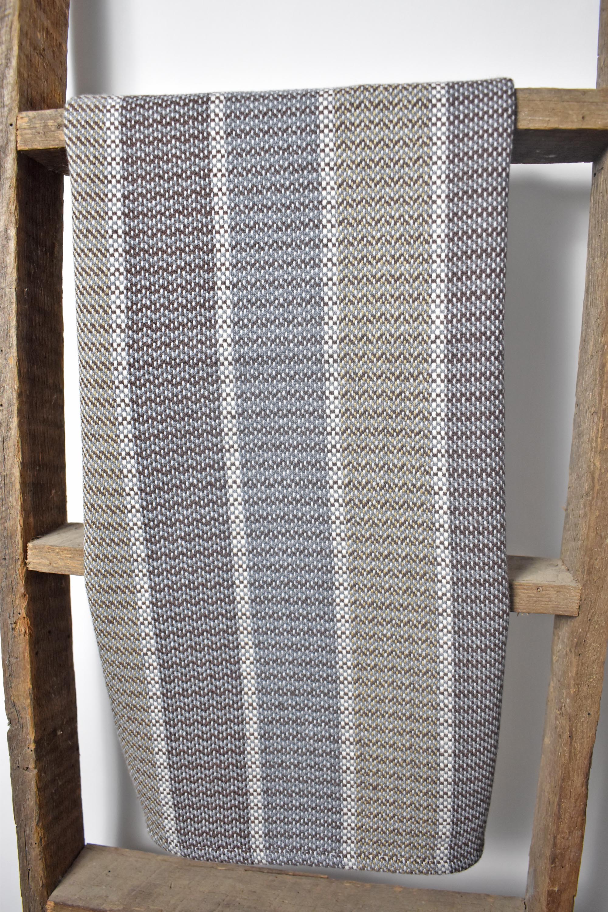 Neutral handwoven tea towel draped over a wooden ladder