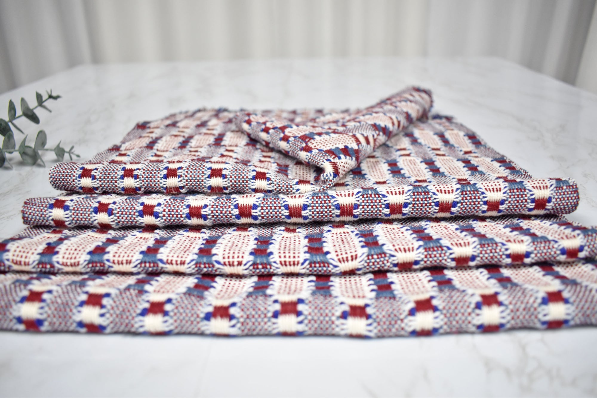 Close-up of 4 patriotic placemats folded on a white table.