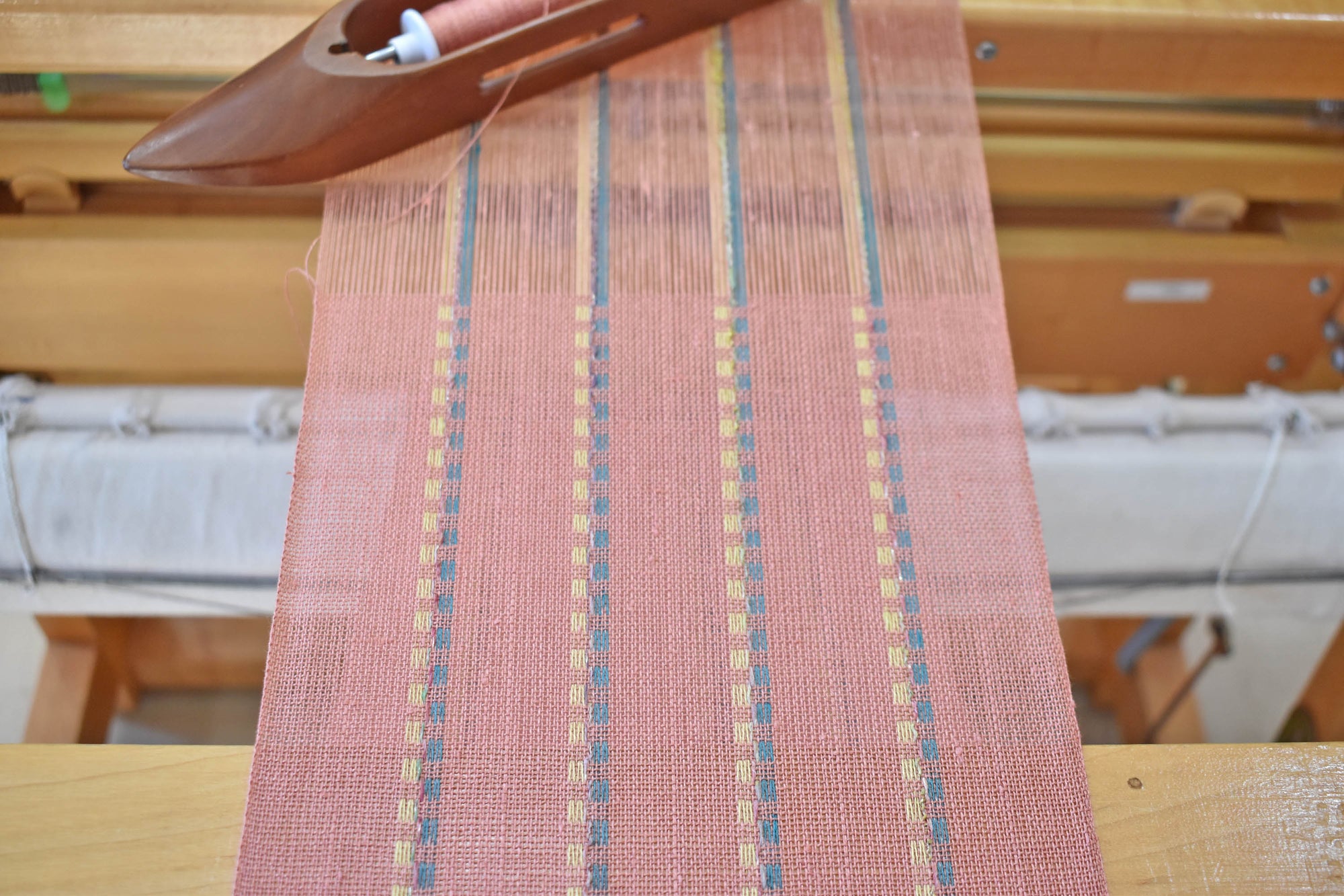 A close-up of the peach scarf on the floor loom as it is woven