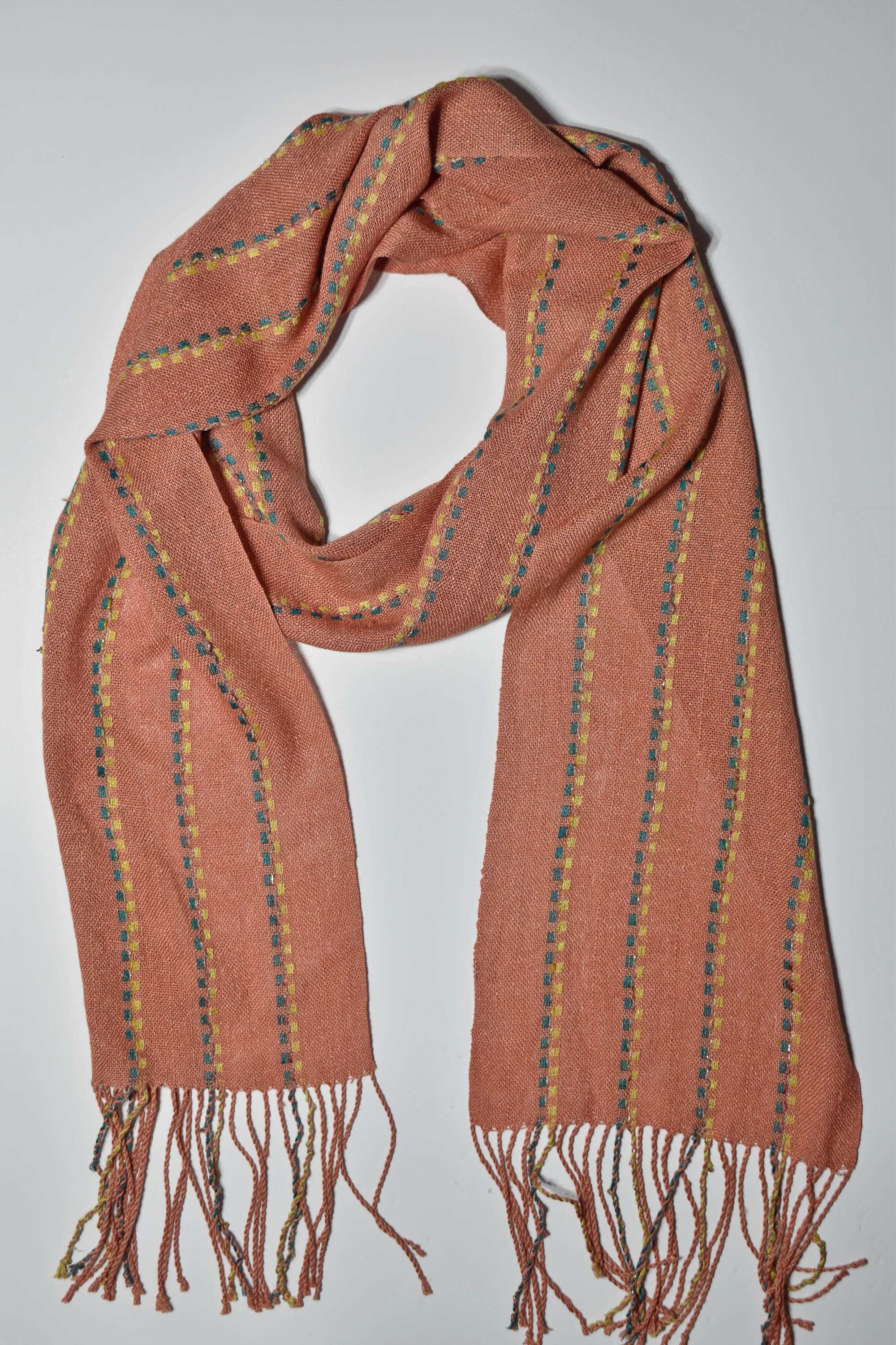 A bird's eye view of the peach handwoven scarf on a white table