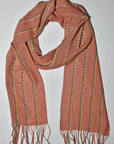 A bird's eye view of the peach handwoven scarf on a white table