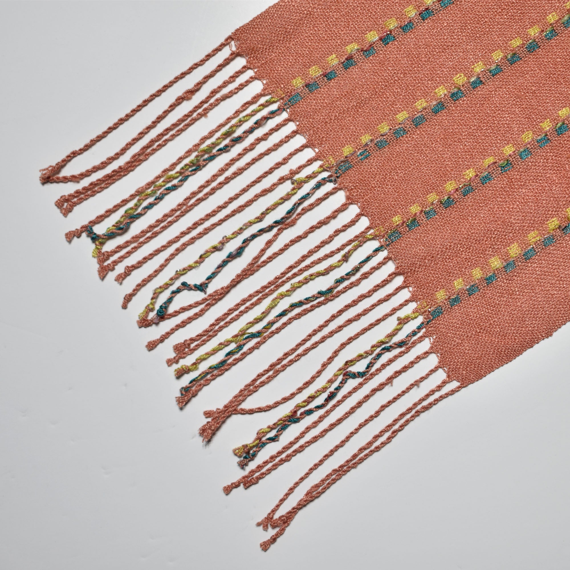 Close-up of the hand twisted fringe on the peach handwoven scarf