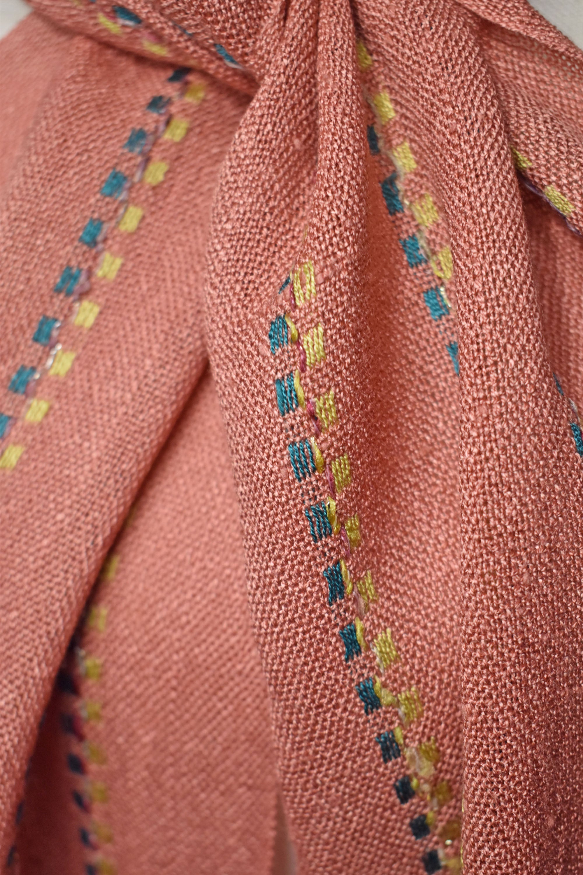 Close-up of the peach handwoven scarf on a model