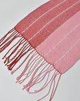 Close-up of the hand twisted fringes on the pink + red handwoven scarf