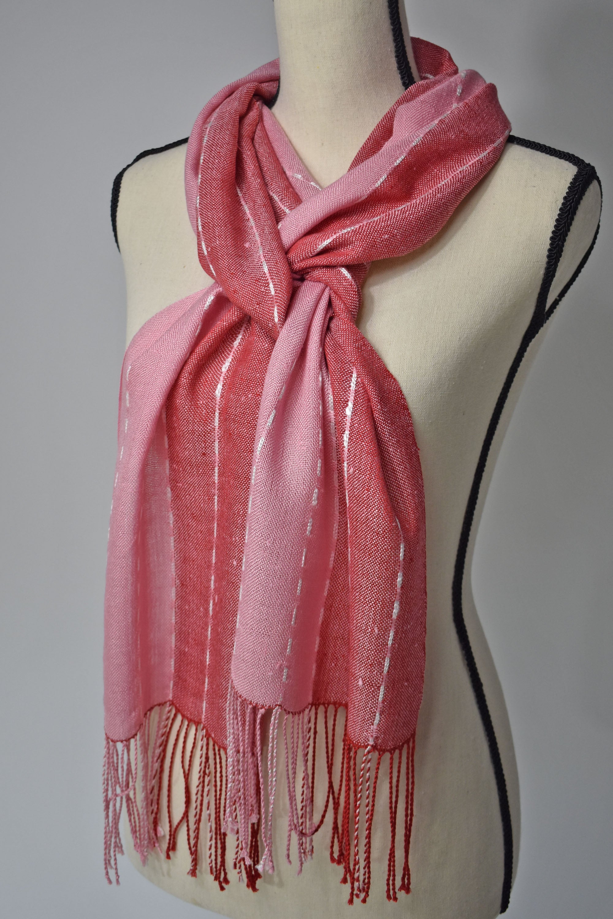 Pink + red handwoven scarf with up-cycled exclusive yarns on a mannequin