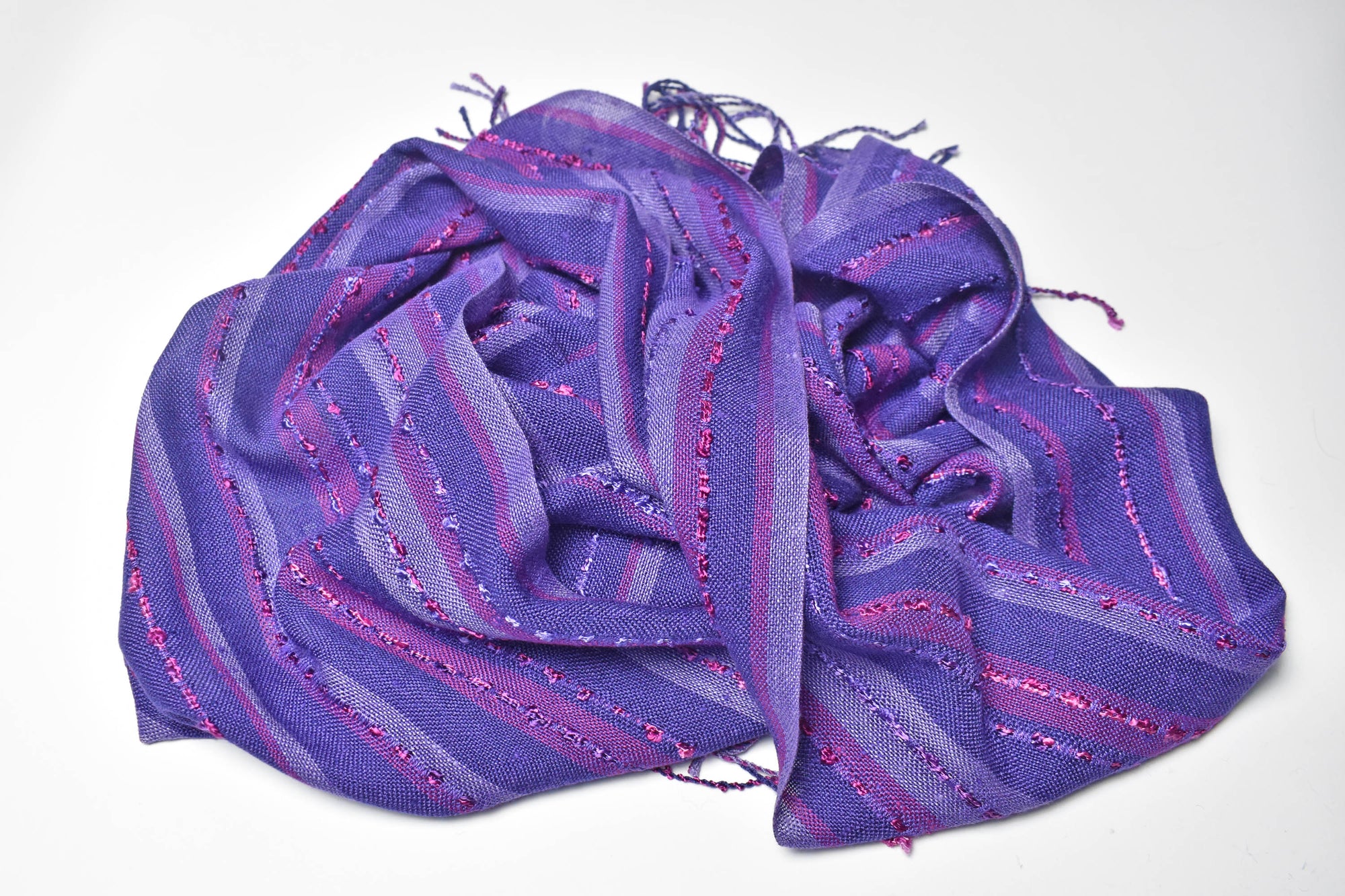 Purple handwoven scarf draped on a white table