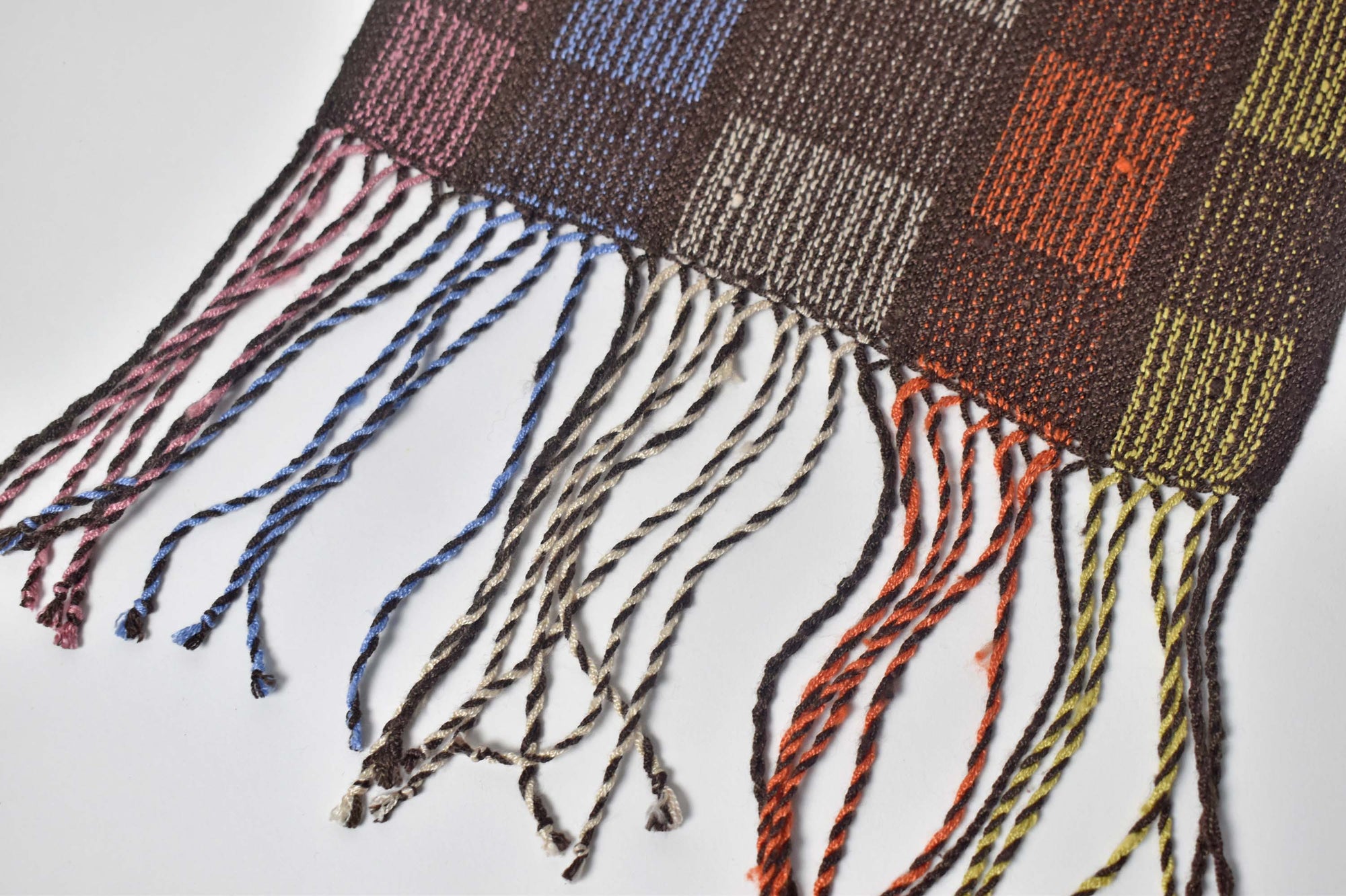 Close-up of hand twisted fringe on a handwoven brown scarf