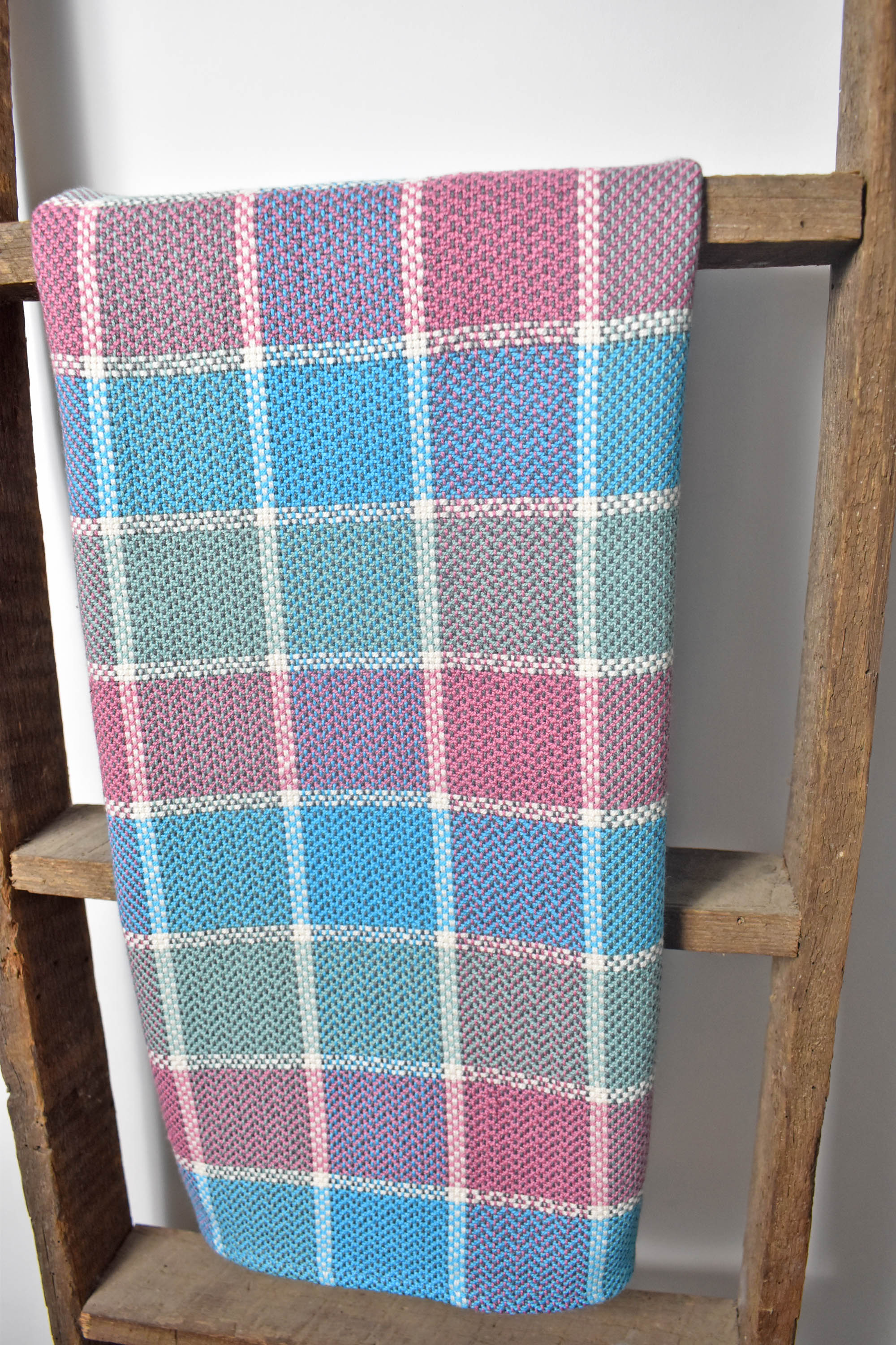 Handwoven plaid cotton towel hanging from a wooden ladder