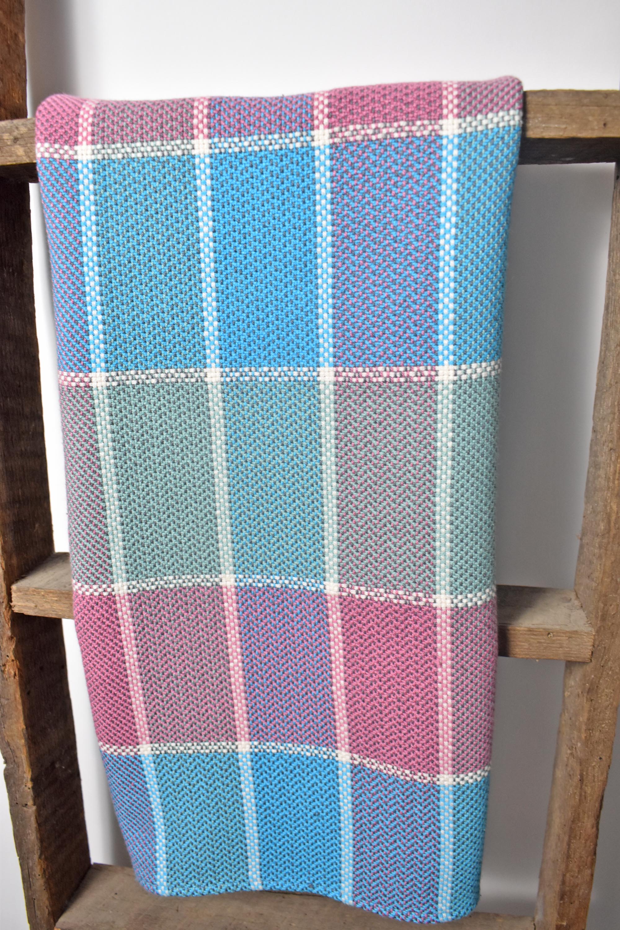 Spring inspired plaid towel draped over a wooden ladder