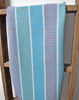 Blue, green, and pink organic cotton towel hanging over a wooden ladder